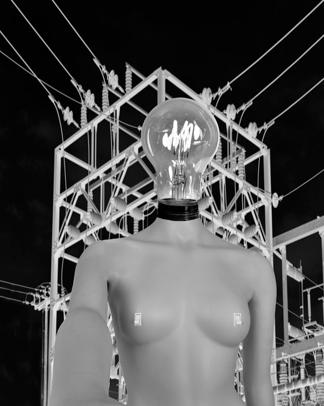 There is a female Luminary with her right arm extended. In the background is an electric transmission line.