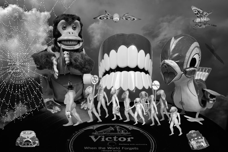 A surreal composite photo. There is an old Victrola record with the title When the World Forgets on it. At the edge of the record are three old fashioned toys. A monkey with symbols, at set of chattering teeth and a wind up metal bird. Overhead are two metal butterfly toys. There is a line of Luminaries with different politically motivated symbols following a large overweight Luminary with a lighthouse for a head and a long Pinocchio nose. They are marching toward a spiderweb with a swastika on it. 